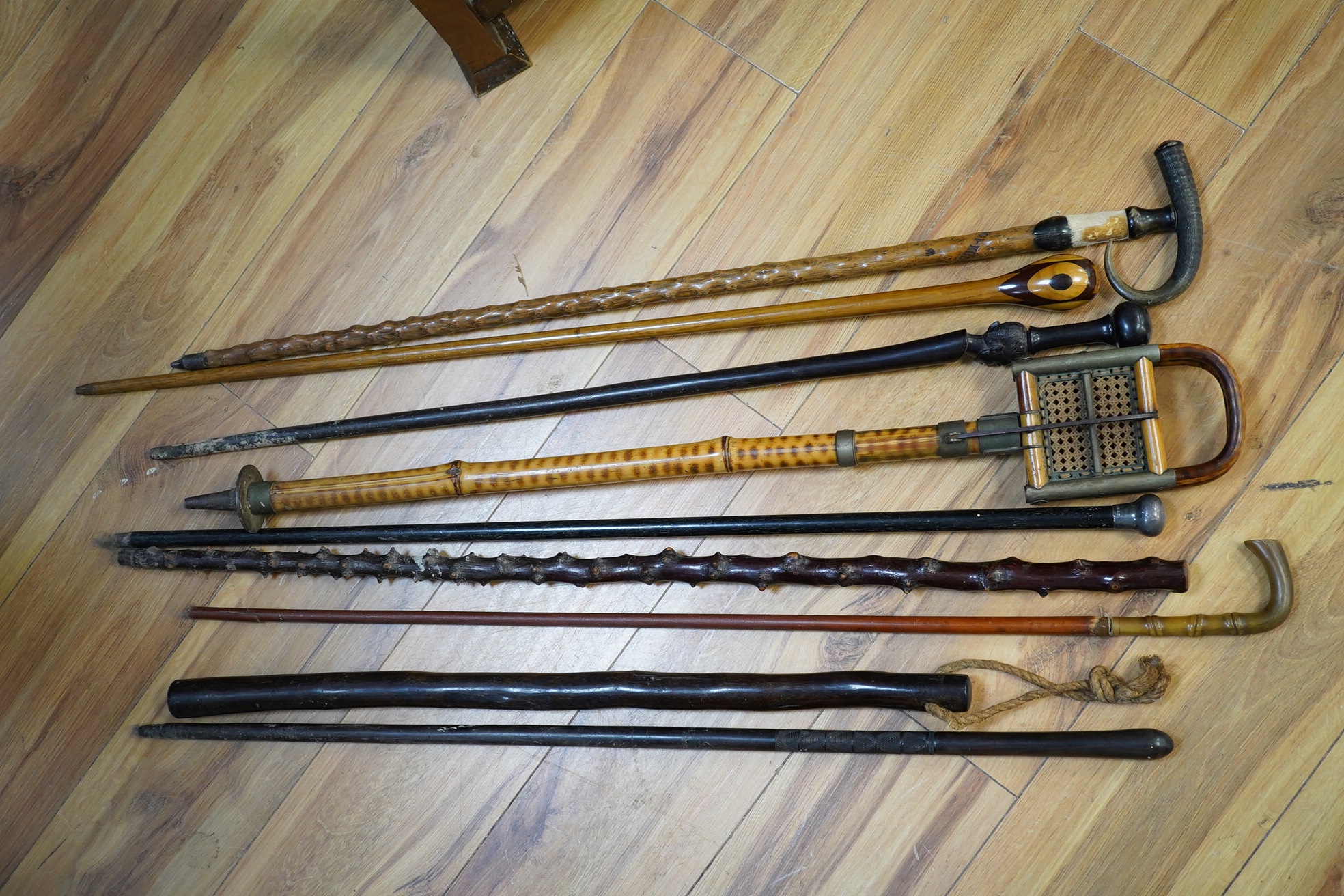 An Edwardian oak stickstand and sundry walking sticks including a bamboo shooting stick, silver topped cane etc. condition varies